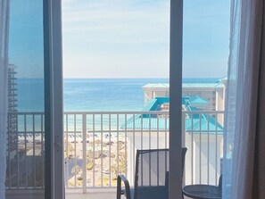 A balcony with a view of the ocean and a resort area.