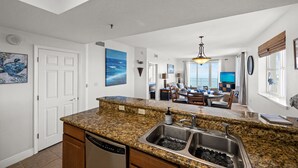 A modern kitchen with granite countertops, stainless steel appliances, and a dining area with a view. - Destin Miramar Sweeping Ocean Views ~ Five Swimming Pools ~ Relaxing! End Unit.  (Destin)
