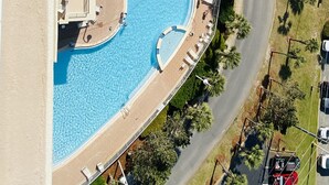 An aerial view of a swimming pool with a circular water feature, surrounded by lounge chairs and a covered seating area. - Destin Miramar Sweeping Ocean Views ~ Five Swimming Pools ~ Relaxing! End Unit.  (Destin)