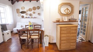 A cozy room with a wooden dining table, chairs, and a wall decorated with woven baskets. - Appartamento La Perla (Marciana Marina)