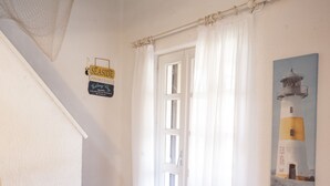 A staircase leading to a room with a white door, a sign on the wall, and a painting of a lighthouse. - Appartamento La Perla (Marciana Marina)