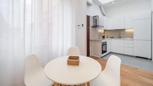 A modern kitchen with white cabinetry, a round dining table with four chairs, and a skylight above. - Accademia (Milan)