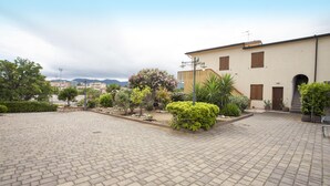 A courtyard with a paved floor, surrounded by a building with multiple windows and a door. - Appartamento Trilo Ornella (Portoferraio)