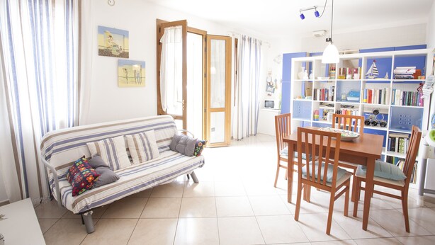 A living room with a sofa, a dining table with chairs, and a bookshelf. - Appartamento Trilo Ornella (Portoferraio)