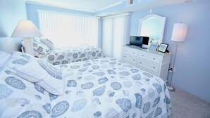 Een slaapkamer met twee bedden, een dressoir, een televisie en een lamp.