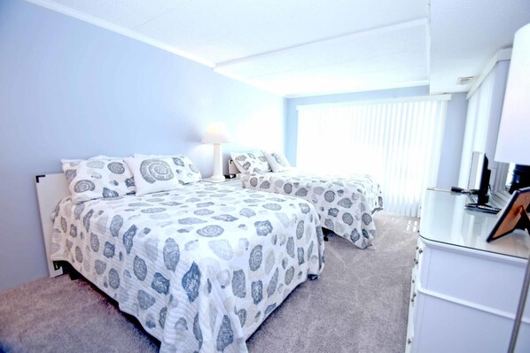 A bedroom with two beds, a desk, and a chair.