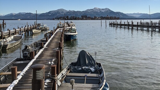 A wooden pier extending into calm water with boats docked at the end.