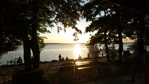A sunset view over a calm body of water, surrounded by trees and a wooden bench area.