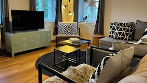 A modern living room with a flat-screen TV, a sofa, a coffee table, and a cabinet.