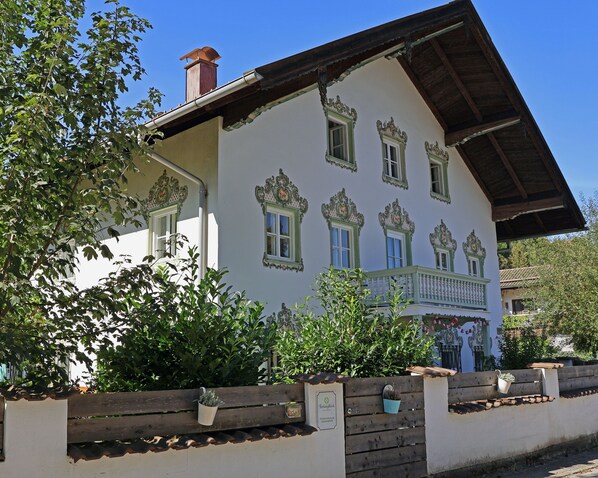 A traditional building with ornate window frames, a wooden balcony, and a chimney. - Gartenglück Vacation Rental - Vacations for the Whole Family - Pets Welcome (Traunstein)