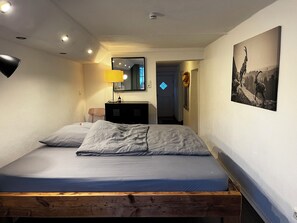 A bedroom with a wooden bed frame, a bedside lamp, a dresser, and a mirror. - Gartenglück Vacation Rental - Vacations for the Whole Family - Pets Welcome (Traunstein)