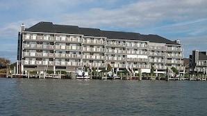 Un hôtel à plusieurs étages, doté de balcons, situé au bord d’un plan d’eau.