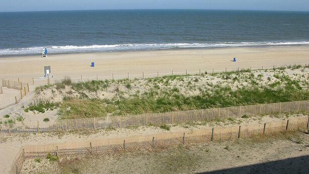 A beach with a wooden fence, a lifeguard tower, and a clear view of the ocean. - Even Keel 404 2 Bedroom Condo by RedAwning (Ocean City)