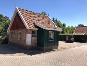 Stylish two-story building with a brick facade and a green upper section, featuring a sloped roof and a small window.