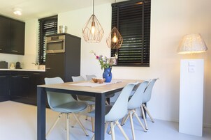Una cocina moderna con armarios oscuros, horno empotrado y comedor con mesa de madera y sillas azul claro.