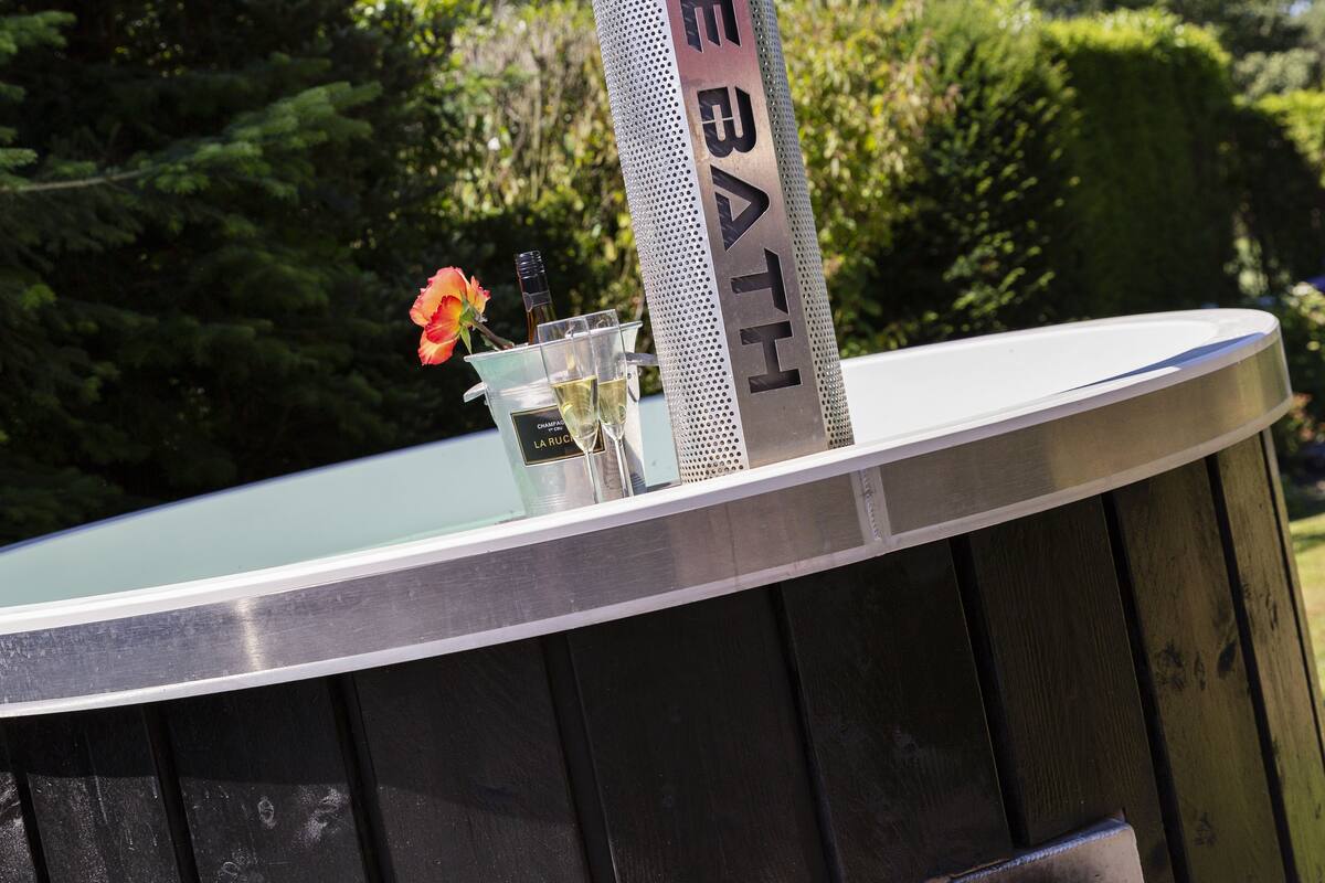 A metal sign with "BATH" on it, a glass container with a flower, and a bottle.