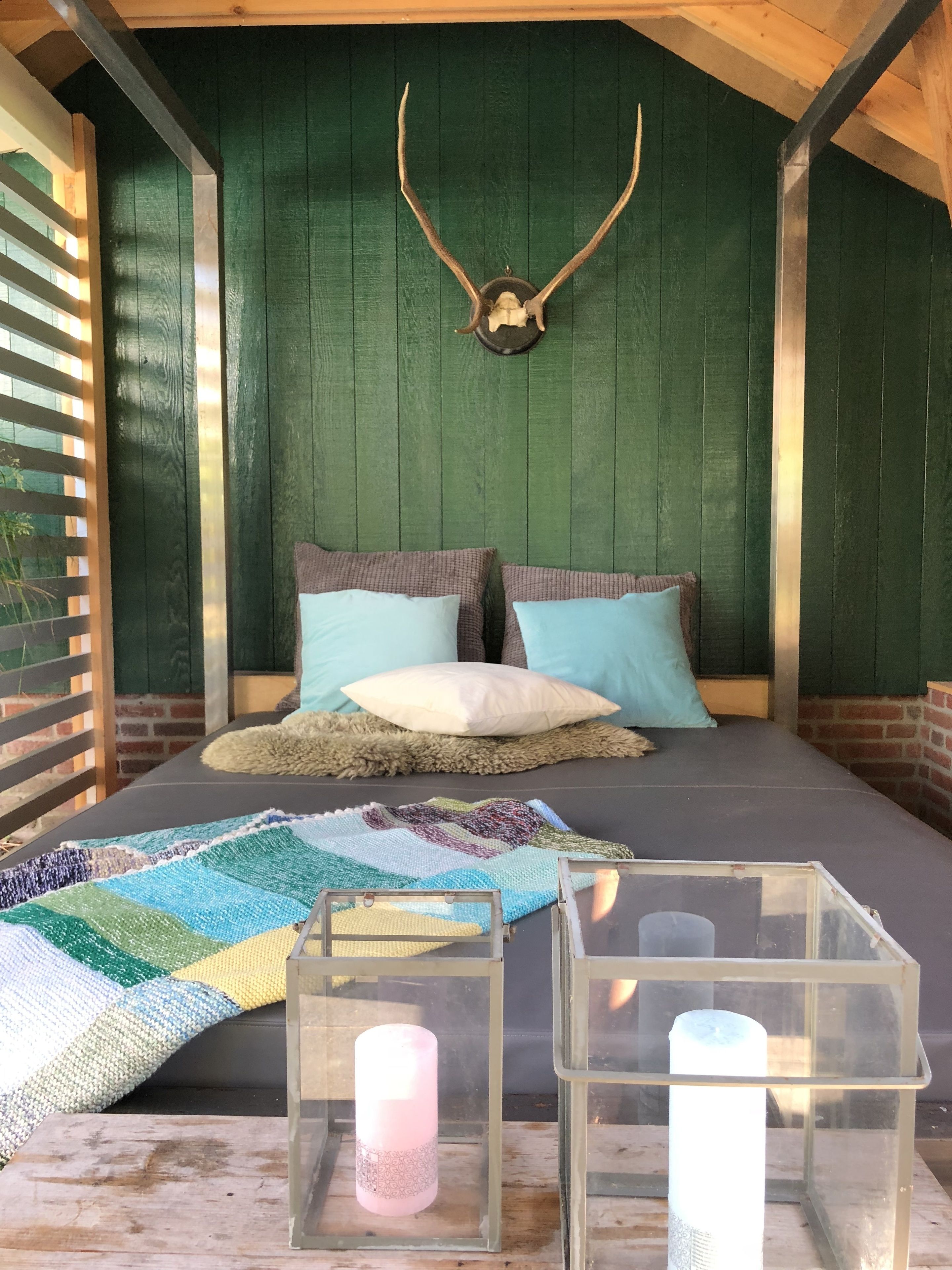 A cozy room with a bed, pillows, a quilt, and two candle holders.