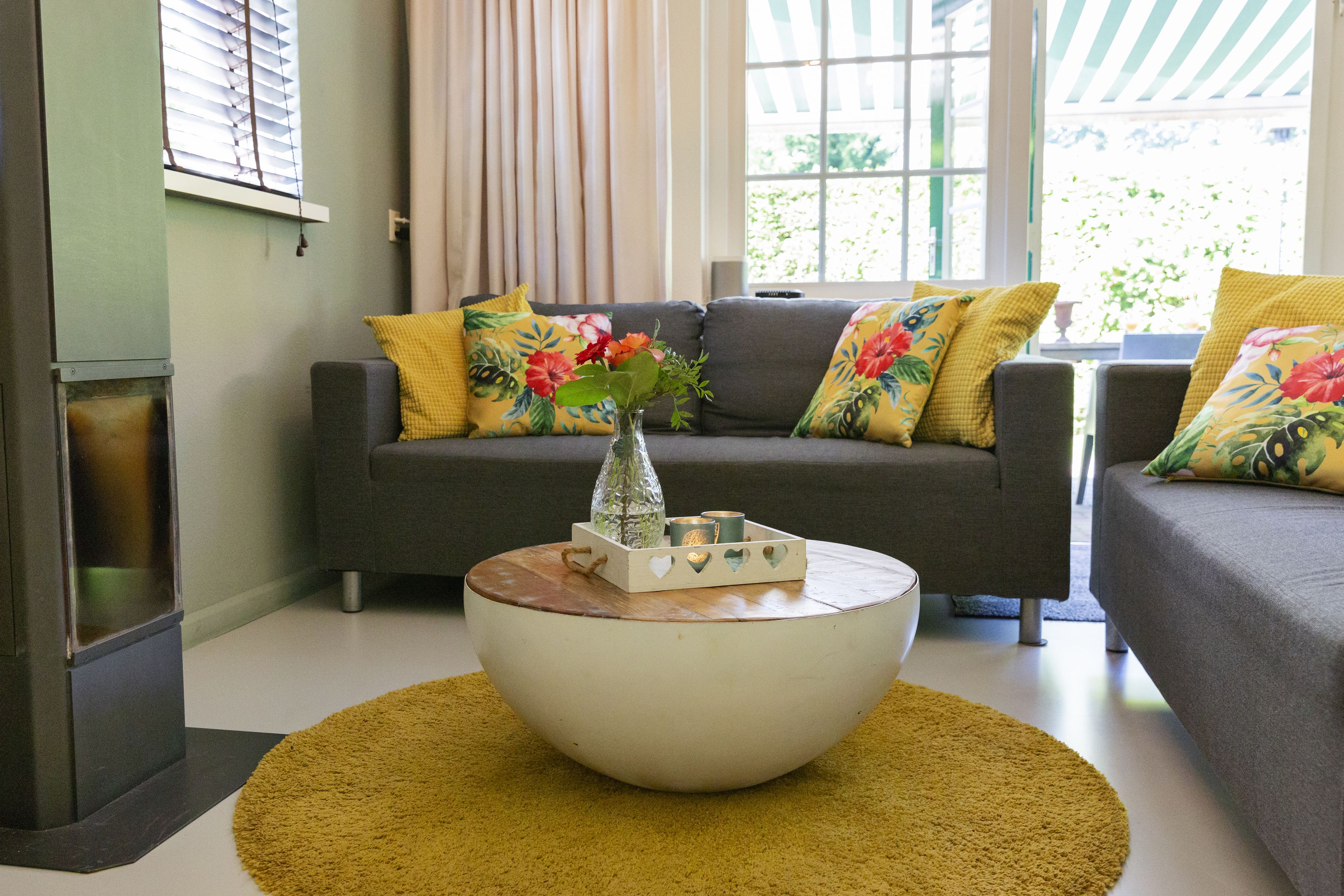 A living room with a sofa set, a coffee table, and a decorative vase with flowers.