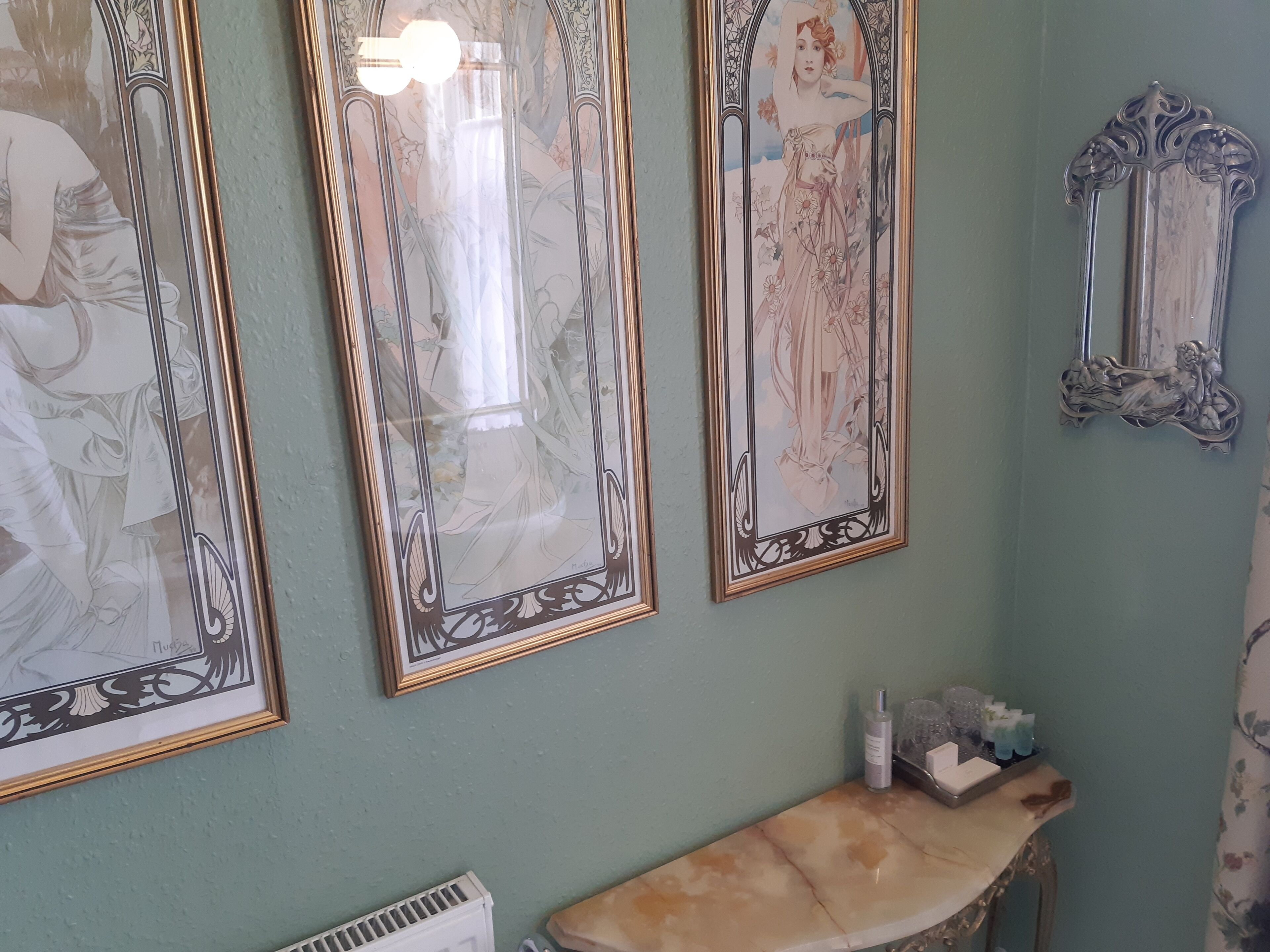 A bathroom with three framed artworks, a marble sink, and a mirror.