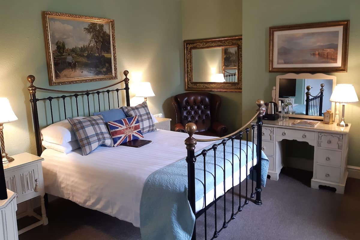 A neatly arranged bedroom with a bed, two bedside tables, a chair, and a dresser.
