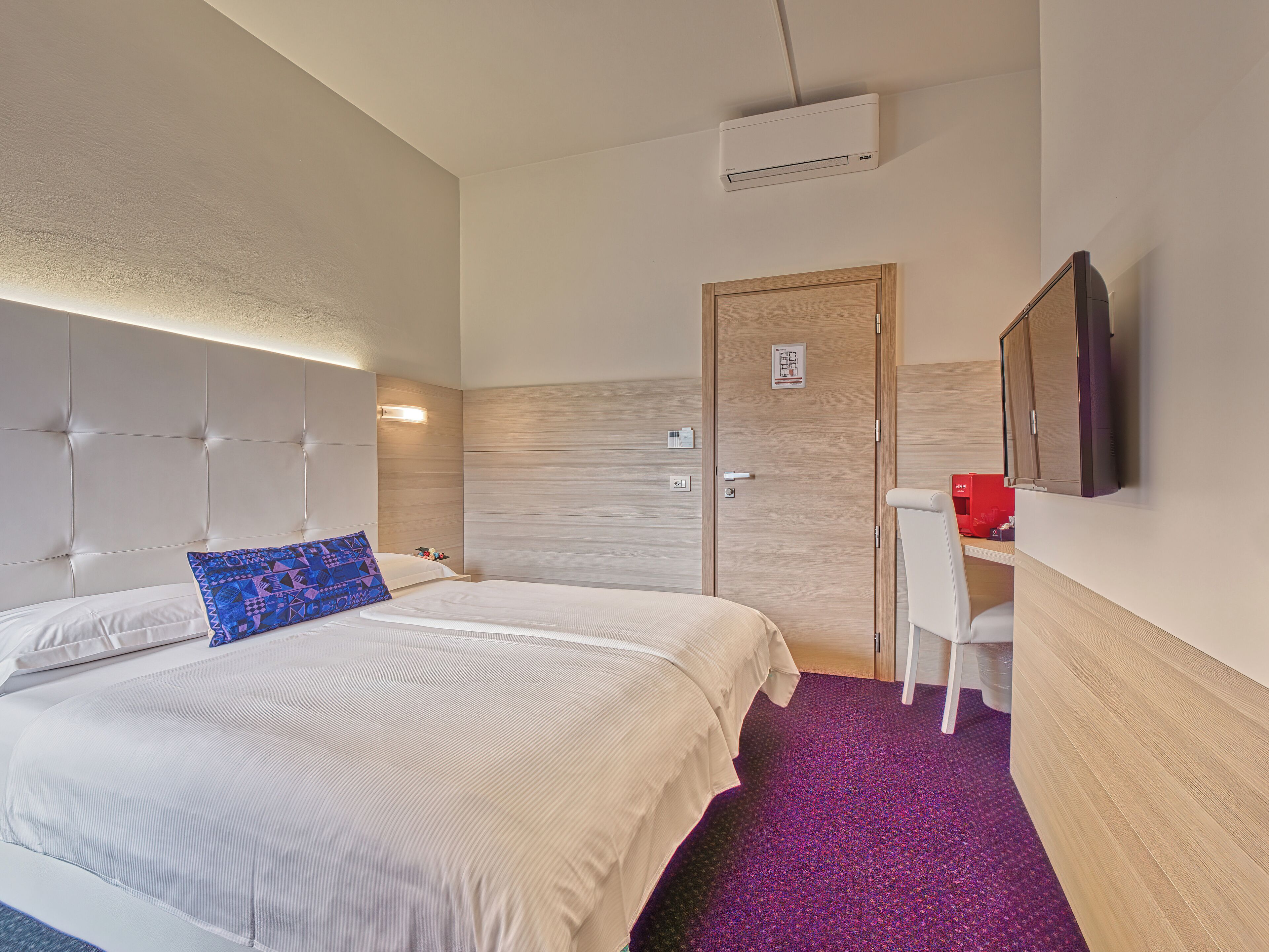 Une chambre d’hôtel équipée d’un lit, d’un bureau, d’une chaise, d’une télévision et d’un appareil de climatisation.