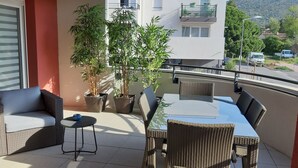 Un balcon agrémenté de meubles en osier, de plantes en pot et offrant une vue sur la rue.