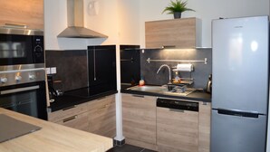 Une cuisine moderne dotée d’appareils électroménagers en acier inoxydable, de meubles en bois et d’un lave-vaisselle encastré.
