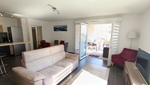 Un salon moderne comprenant un canapé, une table basse, un téléviseur et un coin repas avec des chaises et une table.