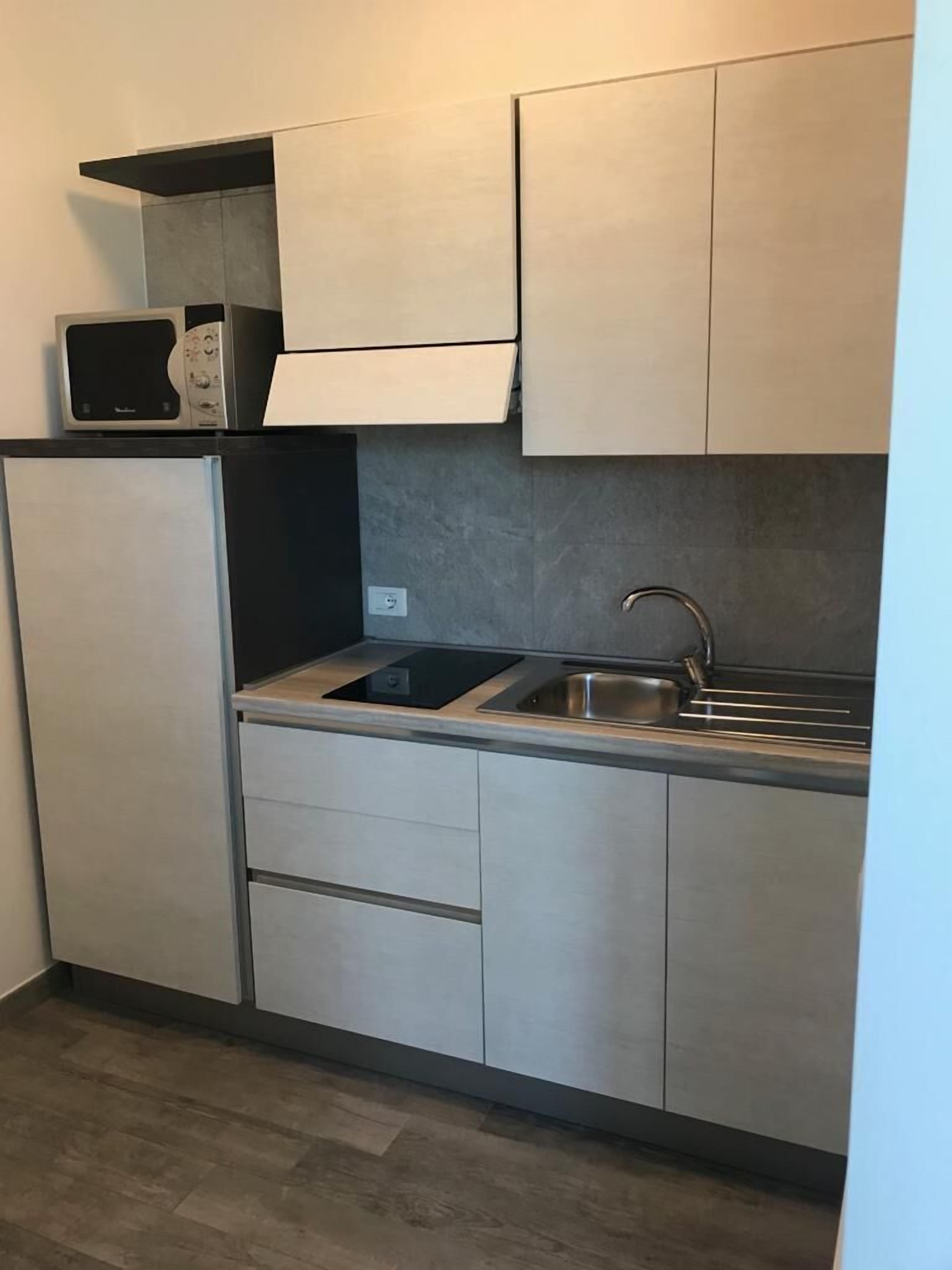 Una cocina compacta equipada con microondas, fregadero y refrigerador.