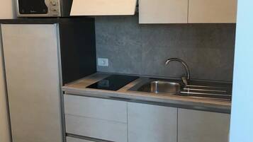 Una cocina compacta equipada con microondas, fregadero y refrigerador.