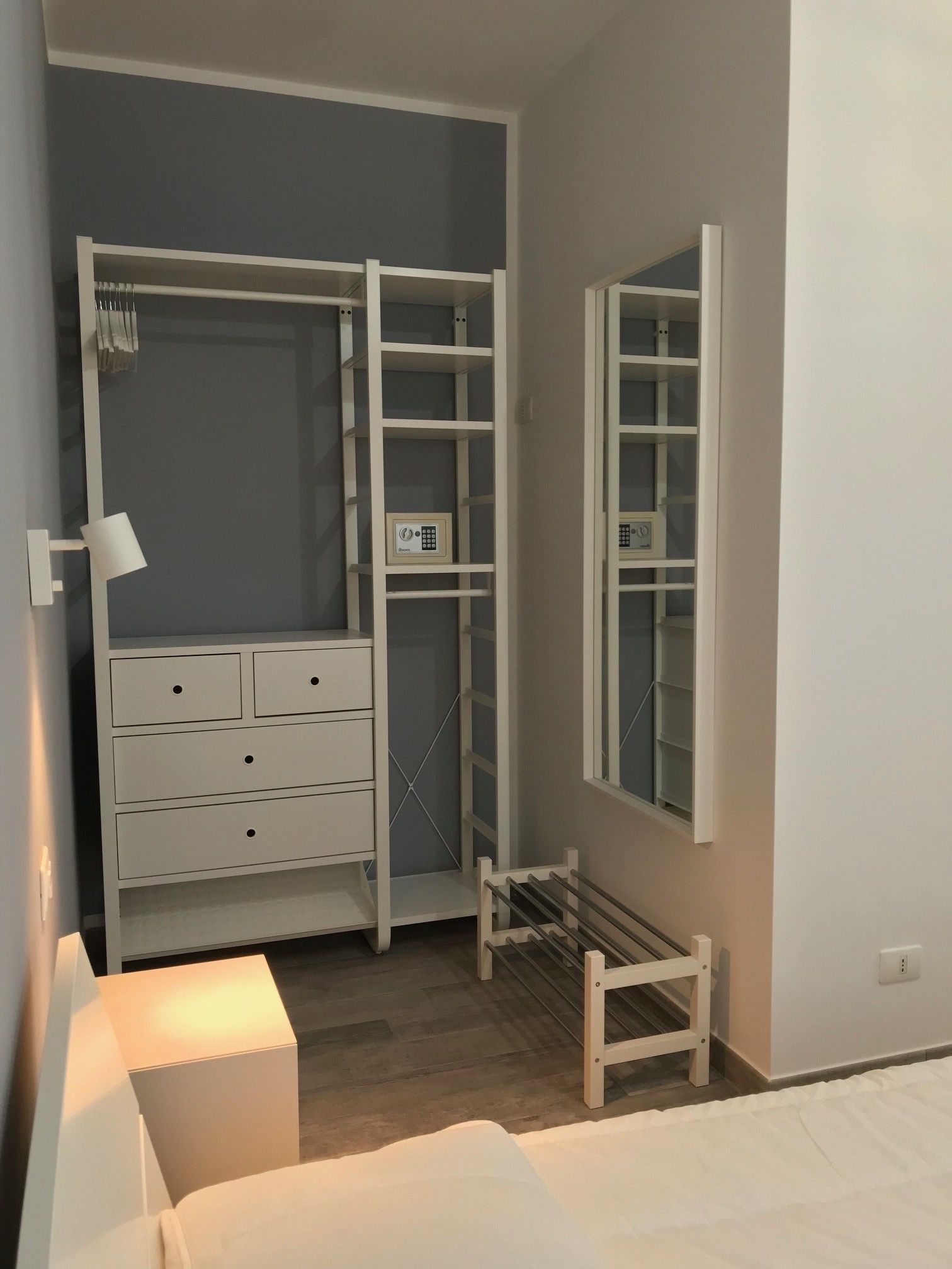 A walk-in closet with a built-in wardrobe, a mirror, and a shoe rack.