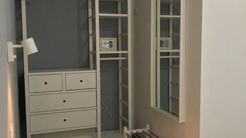 A walk-in closet with a built-in wardrobe, a mirror, and a shoe rack.