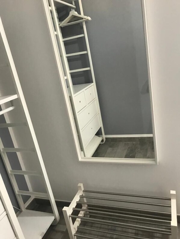 A corner closet with white shelving, a hanging rod, and a small window. - Andrea Case Vacanze L'Ancora (Porto Empedocle)