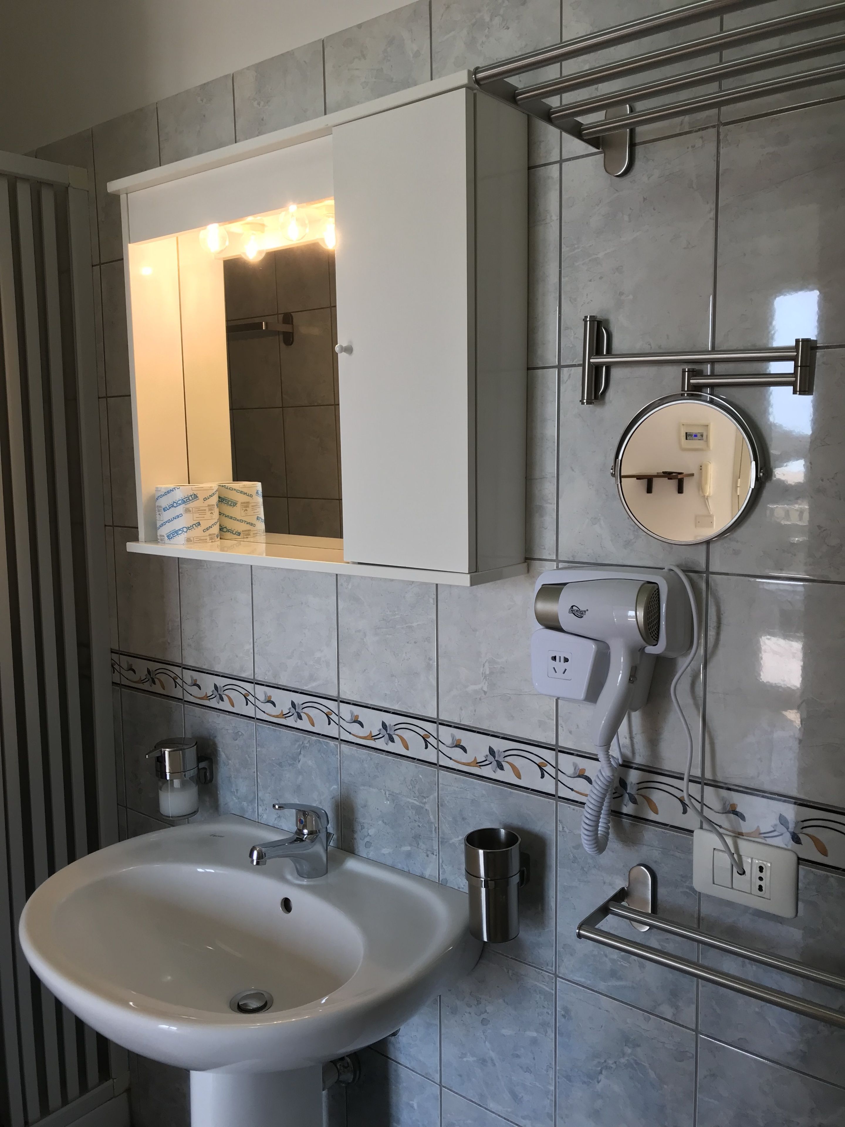 A bathroom with a white sink, a mirror, a towel rack, and a hairdryer.