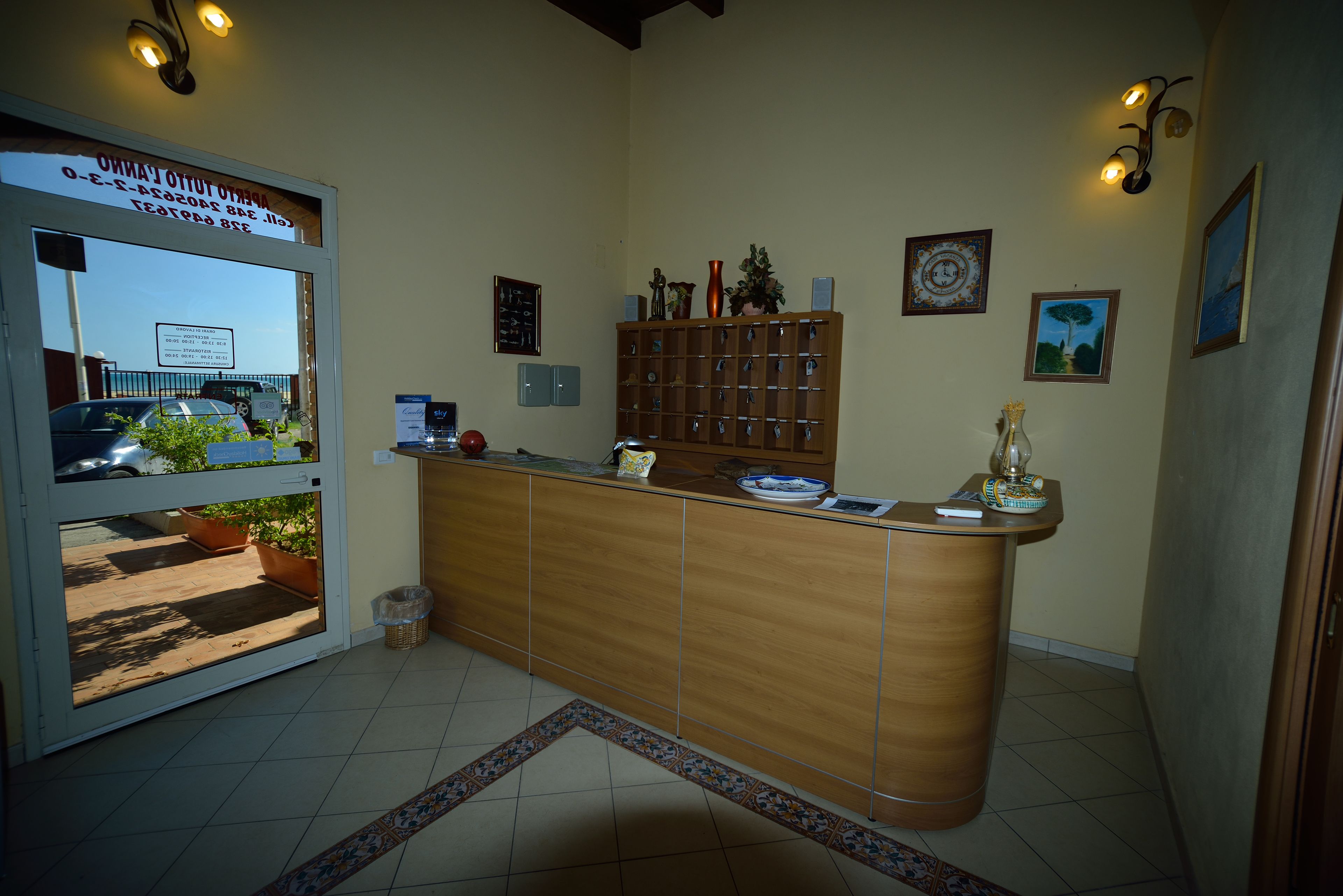A reception area with a wooden counter, a potted plant, and a wall-mounted clock.