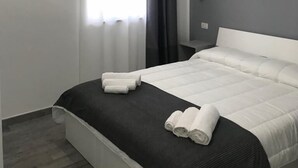 Ein modernes Hotelzimmer mit Bett, Fenster mit Vorhängen, Klimaanlage und Nachttisch.