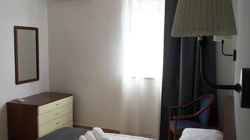 Camera d'albergo con un letto, una cassettiera, una sedia, una lampada da scrivania e un condizionatore d'aria.