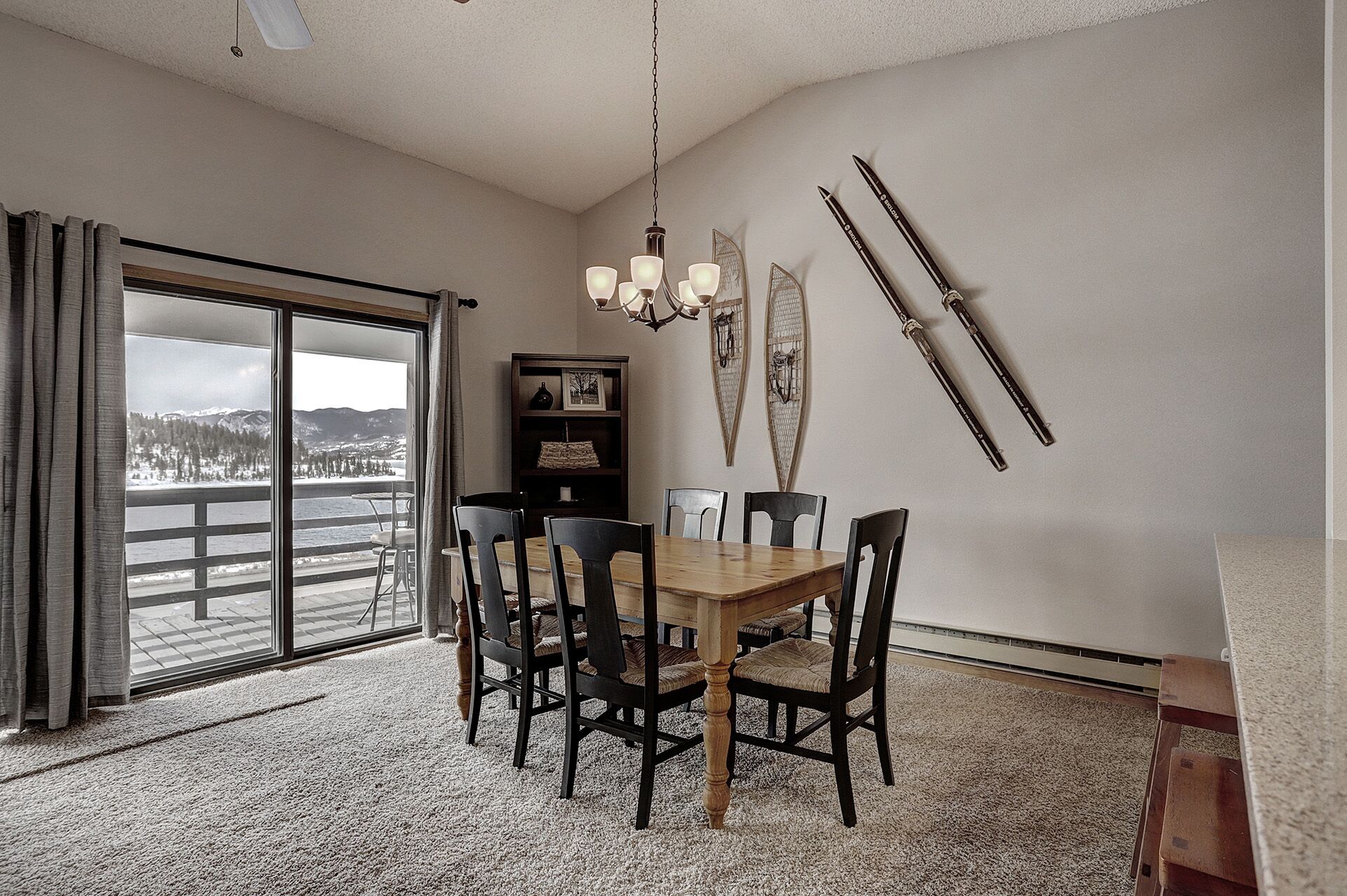 A dining area with a wooden table and chairs, a chandelier, and skis mounted on the wall.