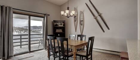 A dining area with a wooden table and chairs, a chandelier, and skis mounted on the wall.