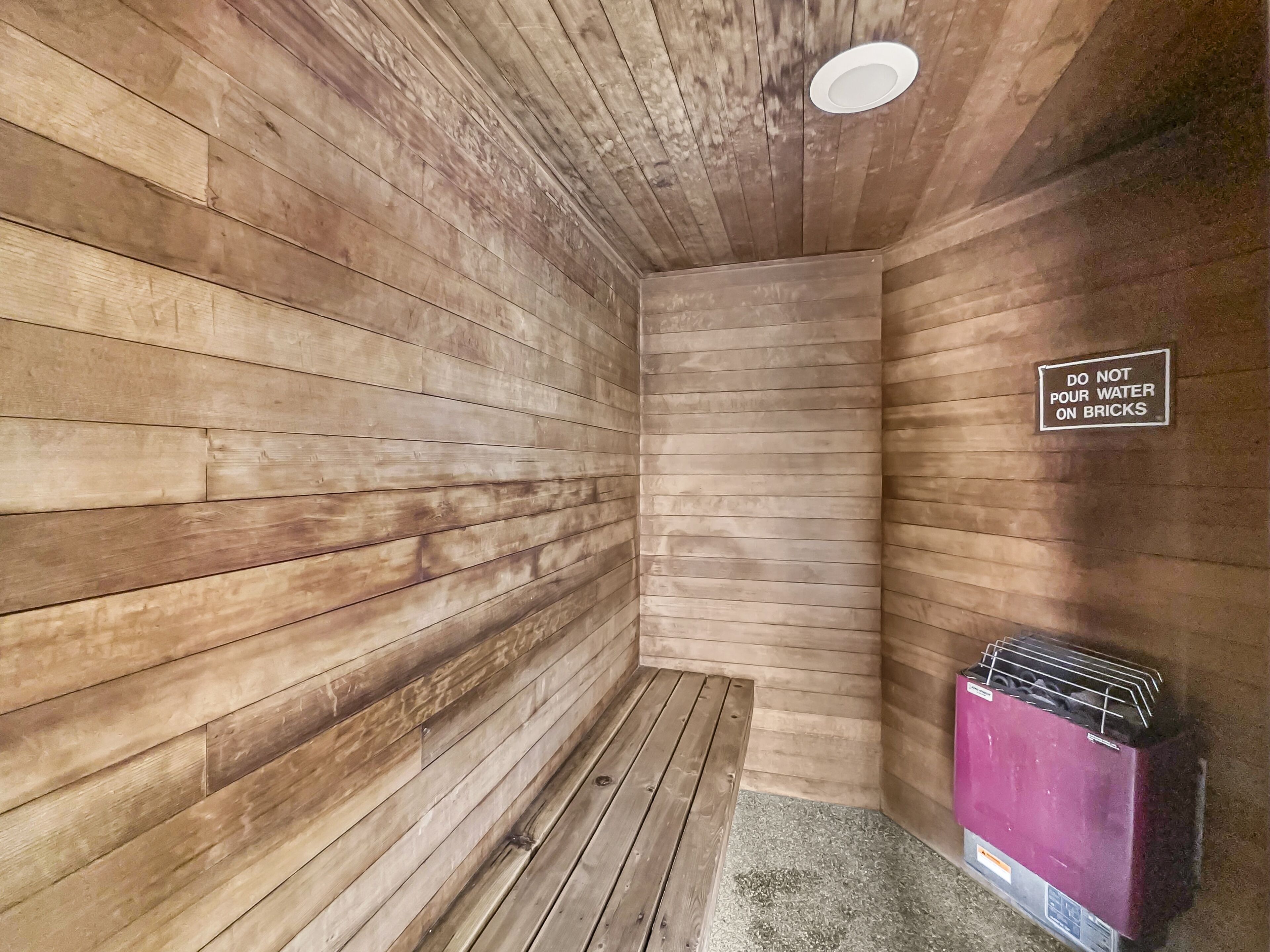 Un sauna con paredes de madera y un cartel que indica no verter agua sobre las piedras.