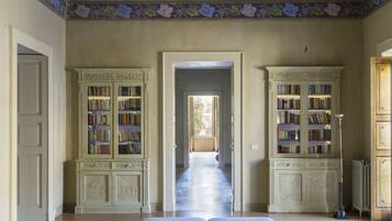 Una habitación amplia con una cama grande, dos libreros y un mural en el techo.
