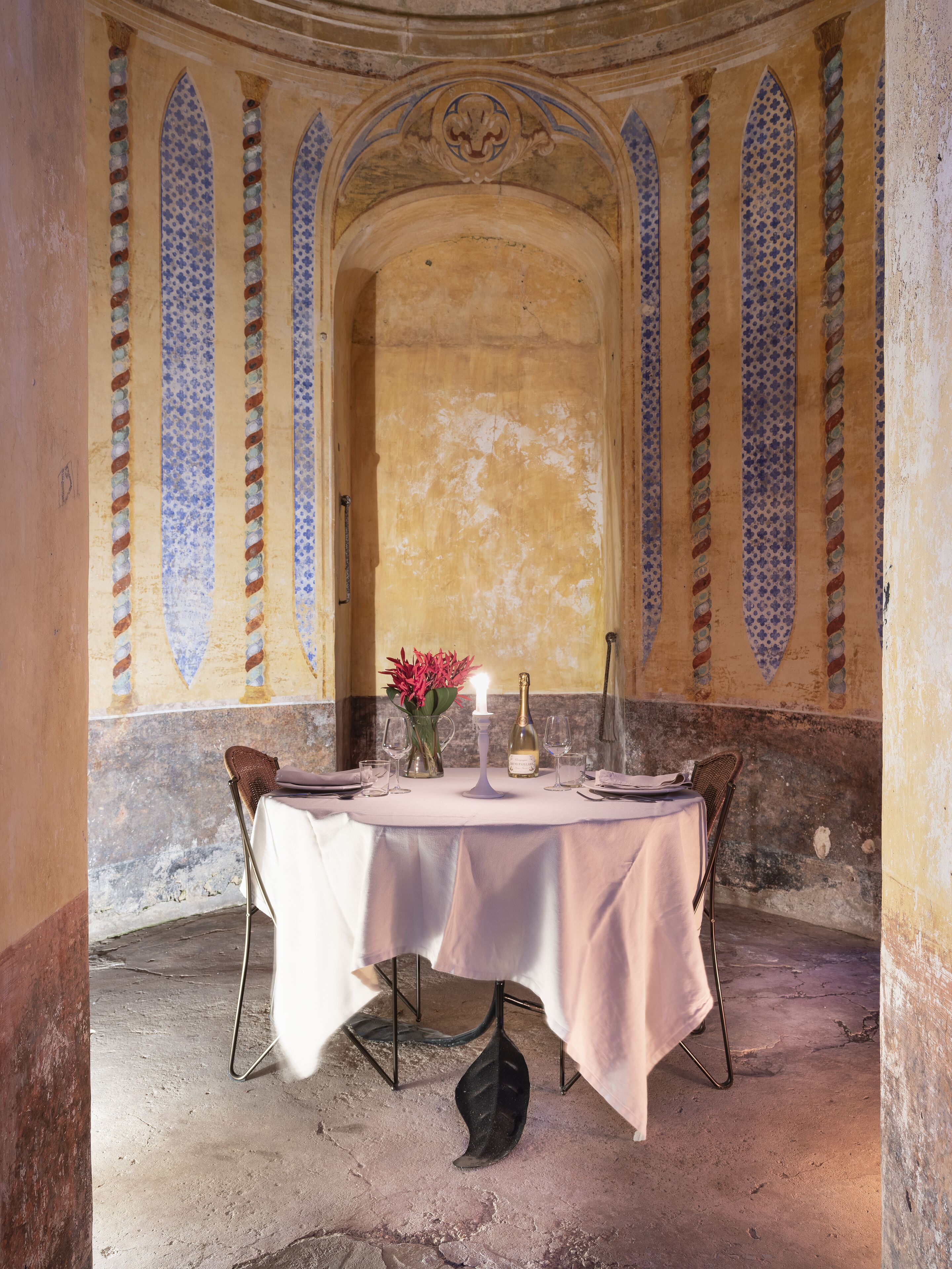 A dining table set for two in a room with arched ceilings and patterned walls.