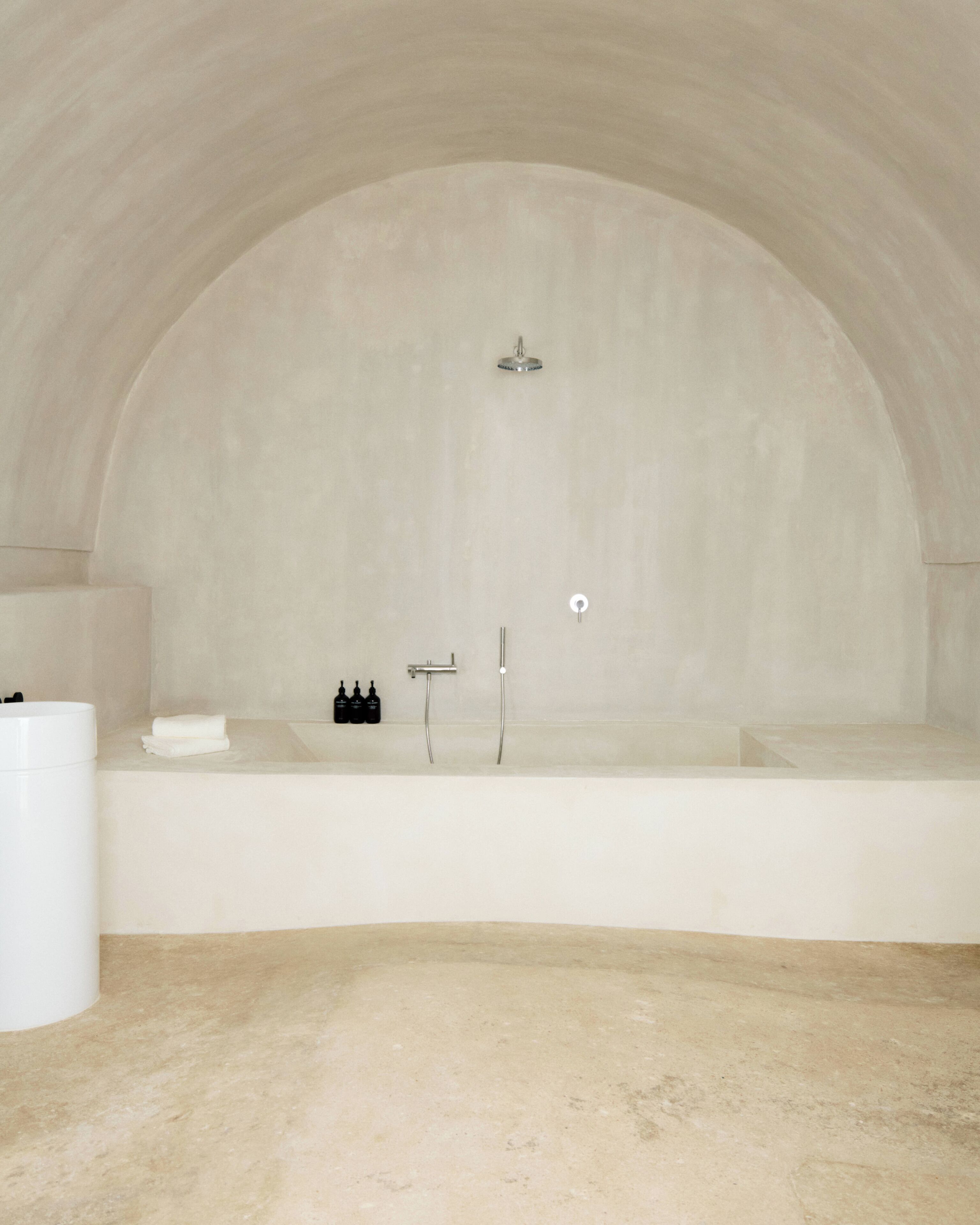 A minimalist bathroom with a freestanding bathtub, a towel rack, and a set of toiletries.