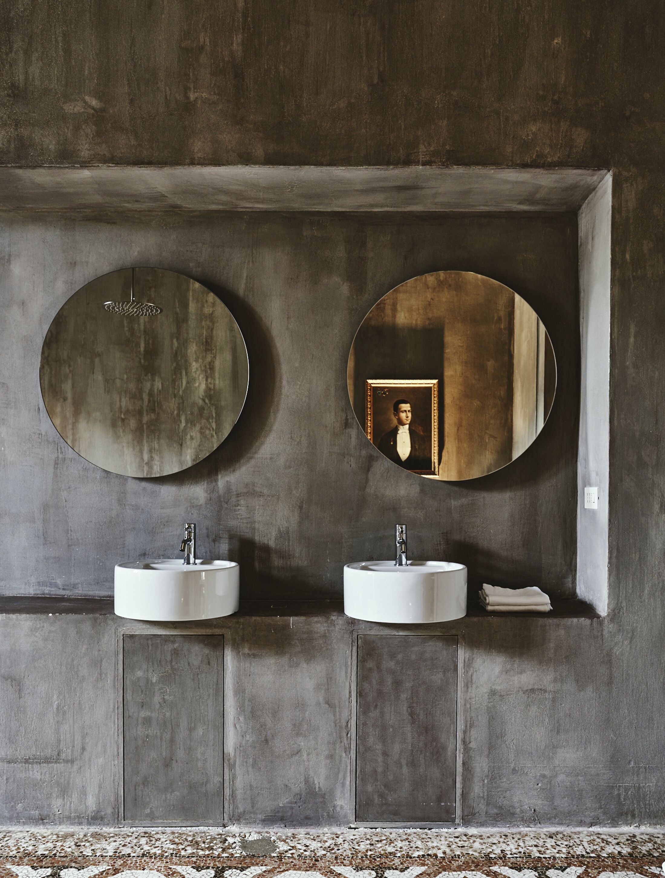A bathroom with two sinks, two large mirrors, and a small shelf with a towel.