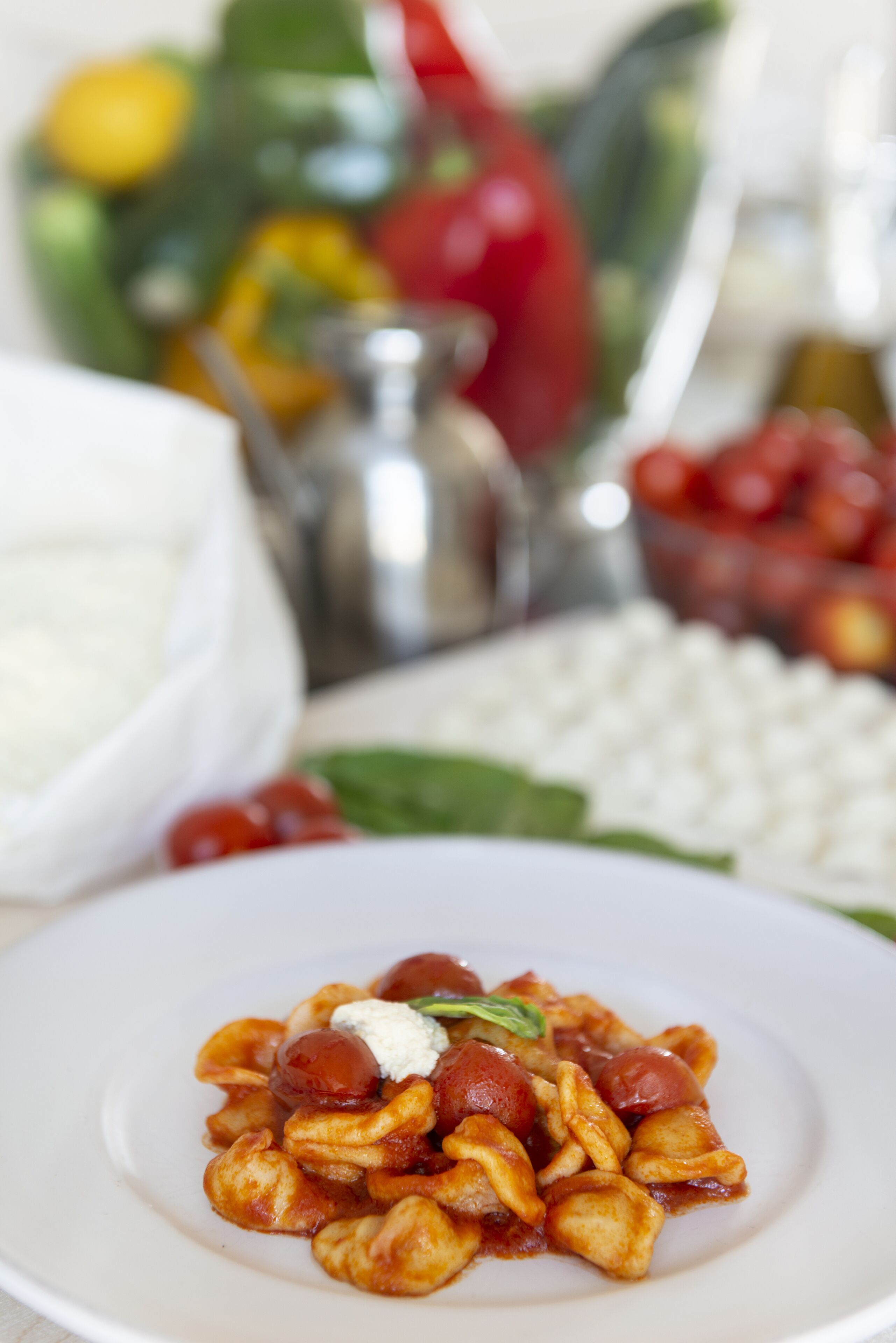 Eine Portion Pasta mit cremiger Soße und Cocktailtomaten, dazu eine Schüssel weißer Käse und ein Gewürzmühle.