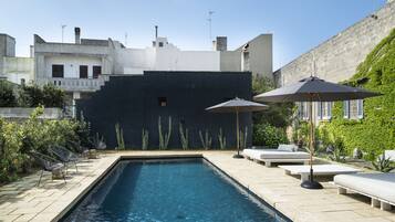 Una piscina al aire libre de temporada, sombrillas
