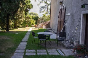 Un patio con una mesa y sillas, un camino de piedra y vista a una escalera que conduce a un edificio.