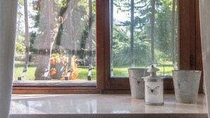 A window with a view of a forest and a metal lantern with a butterfly design on a windowsill. - Verdepiano Bed&Camping (Riva del Garda)