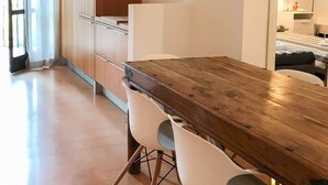 A modern dining area with a wooden table and white chairs, a wooden wardrobe, and a mirror reflecting a bed and a nightstand. - Verdepiano Bed&Camping (Riva del Garda)