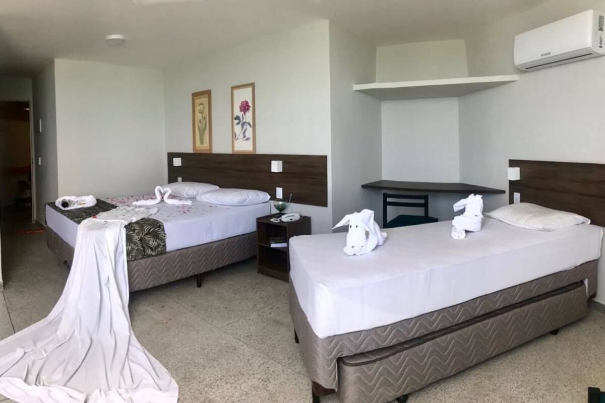 A hotel room with two beds, a desk, and a nightstand.
